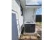 View of air conditioner on small brick foundation next to house with white trim and a partial view of fenced yard at 7834 Treasure Pointe Dr, Port Richey, FL 34668