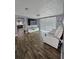 Bright living room features wood floors, white furniture, and a large television with stylish decor elements at 7834 Treasure Pointe Dr, Port Richey, FL 34668