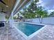 Relaxing backyard oasis showcasing a refreshing in-ground pool with surrounding palm trees and covered patio at 9580 130Th Ave, Largo, FL 33773