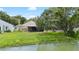 Backyard view of a screened porch, lush green lawn, mature trees, and a waterfront view at 9721 Fredericksburg Rd, Tampa, FL 33635