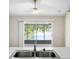 Kitchen sink offering serene views of the lake and backyard through a sliding glass door at 9721 Fredericksburg Rd, Tampa, FL 33635