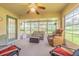 Cozy sunroom with multiple windows, seating arrangements, and a ceiling fan for comfort at 10801 Collar Dr, San Antonio, FL 33576