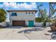Two-story home featuring a brown garage door, turquoise front door and balcony on a bright day at 11285 8Th E St, Treasure Island, FL 33706