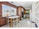 Kitchen with brick walls, large window, white cabinets, and a small table with chairs at 11285 8Th E St, Treasure Island, FL 33706