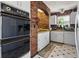 The kitchen featuring brick wall accents, white cabinets, vintage wall oven and matching tile floors at 11285 8Th E St, Treasure Island, FL 33706