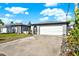 Single-story home with a two-car garage and well-maintained landscaping situated under a bright blue sky with clouds at 13926 Darlene Ave, Hudson, FL 34667