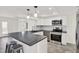 Modern kitchen features white cabinets, tile backsplash, stainless steel appliances, a gray countertop, and a breakfast bar at 13926 Darlene Ave, Hudson, FL 34667