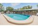 Clean community pool area with clear blue water, surrounded by a wooden fence and shade structures at 1485 Lakeview Rd # 19, Clearwater, FL 33756