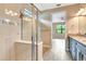 Bright bathroom featuring glass shower doors, wood plank tile flooring, and granite countertops on a dark vanity at 16723 Blackwater Ter, Bradenton, FL 34202