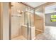 A modern glass shower enclosure in a bathroom, next to a room featuring natural light and a ceiling fan at 16723 Blackwater Ter, Bradenton, FL 34202