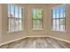 Bright bedroom featuring wood-look floors and three large windows with blinds at 16723 Blackwater Ter, Bradenton, FL 34202