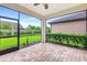 Covered brick patio offering an outdoor living space with a screened-in enclosure and view of the green backyard at 16723 Blackwater Ter, Bradenton, FL 34202