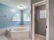 Bright bathroom featuring a soaking tub with marble surround and arched windows for natural light at 1914 Henley Rd, Lutz, FL 33558