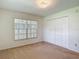 Well-lit bedroom features carpet, window and closet with traditional panel doors at 1914 Henley Rd, Lutz, FL 33558