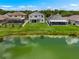 Aerial view of the backyard with a pond, green grass, and a screened-in pool in the neighboring property at 1933 Fruitridge St, Brandon, FL 33510