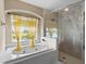 Bright bathroom featuring a large tub under a window and a glass-enclosed shower at 1933 Fruitridge St, Brandon, FL 33510