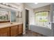 Bright bathroom featuring a vanity and a tub under a window and a glass-enclosed shower at 1933 Fruitridge St, Brandon, FL 33510