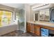 Bright bathroom featuring a vanity and a tub under a window and a glass-enclosed shower at 1933 Fruitridge St, Brandon, FL 33510