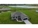 Aerial view of a modern home with a well-manicured lawn, a lake, and a dark roof at 2330 Hiers Rd, Dover, FL 33527