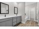 Elegant bathroom featuring double sink vanity, framed mirrors, grey cabinets, and a soaking tub at 2414 Hiers Rd, Dover, FL 33527