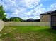 A large fenced yard with grass and partial view of the house at 24815 Lambrusco Loop, Lutz, FL 33559