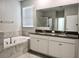 Bathroom showcasing a soaking tub, a double sink vanity with granite countertops, and a glass-enclosed shower at 24815 Lambrusco Loop, Lutz, FL 33559