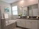 Bathroom with a soaking tub, a double sink vanity with granite countertops, and decorative plants at 24815 Lambrusco Loop, Lutz, FL 33559