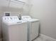 Laundry room showcasing a side-by-side washer and dryer and a metal storage shelf at 24815 Lambrusco Loop, Lutz, FL 33559