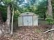 Utility shed with double doors surrounded by trees and green undergrowth at 25425 Olympia Rd, Brooksville, FL 34601