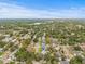 An aerial view of a home in a tree-lined suburban neighborhood, with a distant lake and clear skies above at 2554 Lake Ellen Cir, Tampa, FL 33618