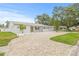 Wide brick driveway leading to a white brick home, complemented by lush green lawn and mature trees at 2554 Lake Ellen Cir, Tampa, FL 33618