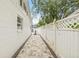 A well-maintained side yard with a stone pathway and a white privacy fence, offering a clean and defined outdoor space at 2554 Lake Ellen Cir, Tampa, FL 33618