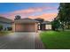 Charming single-story home featuring a well-manicured lawn, two car garage, and a beautiful sunset sky at 2708 Dolphin Watch Ct, Holiday, FL 34691