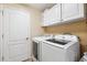 Clean laundry room with overhead storage and modern washer and dryer at 2708 Dolphin Watch Ct, Holiday, FL 34691