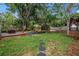 Landscaped backyard with a wooden deck, lush green grass, mature trees, and stepping stones at 300 33Rd N Ave, St Petersburg, FL 33704