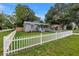 Cozy home featuring a white picket fence, grass lawn and colorful flowers at 300 33Rd N Ave, St Petersburg, FL 33704