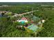 This aerial view features a community pool and other sports courts in a wooded area with ample parking at 30918 Burleigh Dr, Wesley Chapel, FL 33543