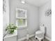 Cozy bathroom with decorative flower art, toilet and a window with blinds to allow for natural light at 30918 Burleigh Dr, Wesley Chapel, FL 33543