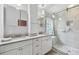 Bright bathroom with double sink vanity, granite countertops, stylish mirror cabinets, and tiled walk-in shower at 30918 Burleigh Dr, Wesley Chapel, FL 33543