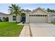Well-maintained home featuring a two-car garage, lush lawn, and a welcoming blue front door at 30918 Burleigh Dr, Wesley Chapel, FL 33543