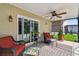 Covered lanai with comfortable wicker furniture, ceiling fan, and views of the lush backyard at 30918 Burleigh Dr, Wesley Chapel, FL 33543