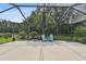 Spacious screened patio featuring blue Adirondack chairs, lush landscaping, and serene backyard views at 30918 Burleigh Dr, Wesley Chapel, FL 33543