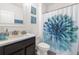 Bright bathroom featuring a floral shower curtain, vanity with a white countertop, and decorative wall art at 30936 Summer Sun Loop, Wesley Chapel, FL 33545