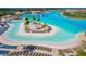 Aerial view of community pool featuring a sandy beach, cabanas, and lounge chairs for relaxing at 30936 Summer Sun Loop, Wesley Chapel, FL 33545