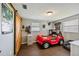 Playful bedroom featuring a red racecar bed, a sliding barn door, and wood-look floors at 3217 Mott Rd, Dover, FL 33527