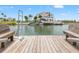 Waterfront view from a wooden dock with seating, showcasing a luxury home and boats at 3226 Gardenia Dr, Hernando Beach, FL 34607