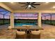 Covered outdoor patio with dining area, overlooking a swimming pool and lush green landscape at sunset at 33774 Castaway Loop, Wesley Chapel, FL 33543