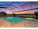 Sparkling screened-in pool and spa surrounded by a brick patio and beautiful landscaping at 33774 Castaway Loop, Wesley Chapel, FL 33543