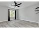 Neutral bedroom featuring wood-look floors, a ceiling fan, a large window, and modern shelving accents at 3595 41St S Ln # L, St Petersburg, FL 33711