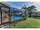 An inviting screened-in pool surrounded by tropical landscaping with a view of the pond at 395 Forest Park Rd, Oldsmar, FL 34677